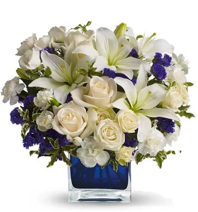 Nothing better to inspire a bouquet than nature itself! Our Clear Blue Skies Bouquet is arranged to reflect the beauty of a beautiful day where the sun is shining without a cloud in the sky! Pearly white lilies surrounded by creme white roses purple statice invoke happiness in any beholder, whether they're displayed in a home or at an office, they're perfect for any kind of day.

Includes:
* Creme Roses
* White Asiatic Lilies
* White Miniature Carnations
* Purple Statice
* Blue Cube Vase